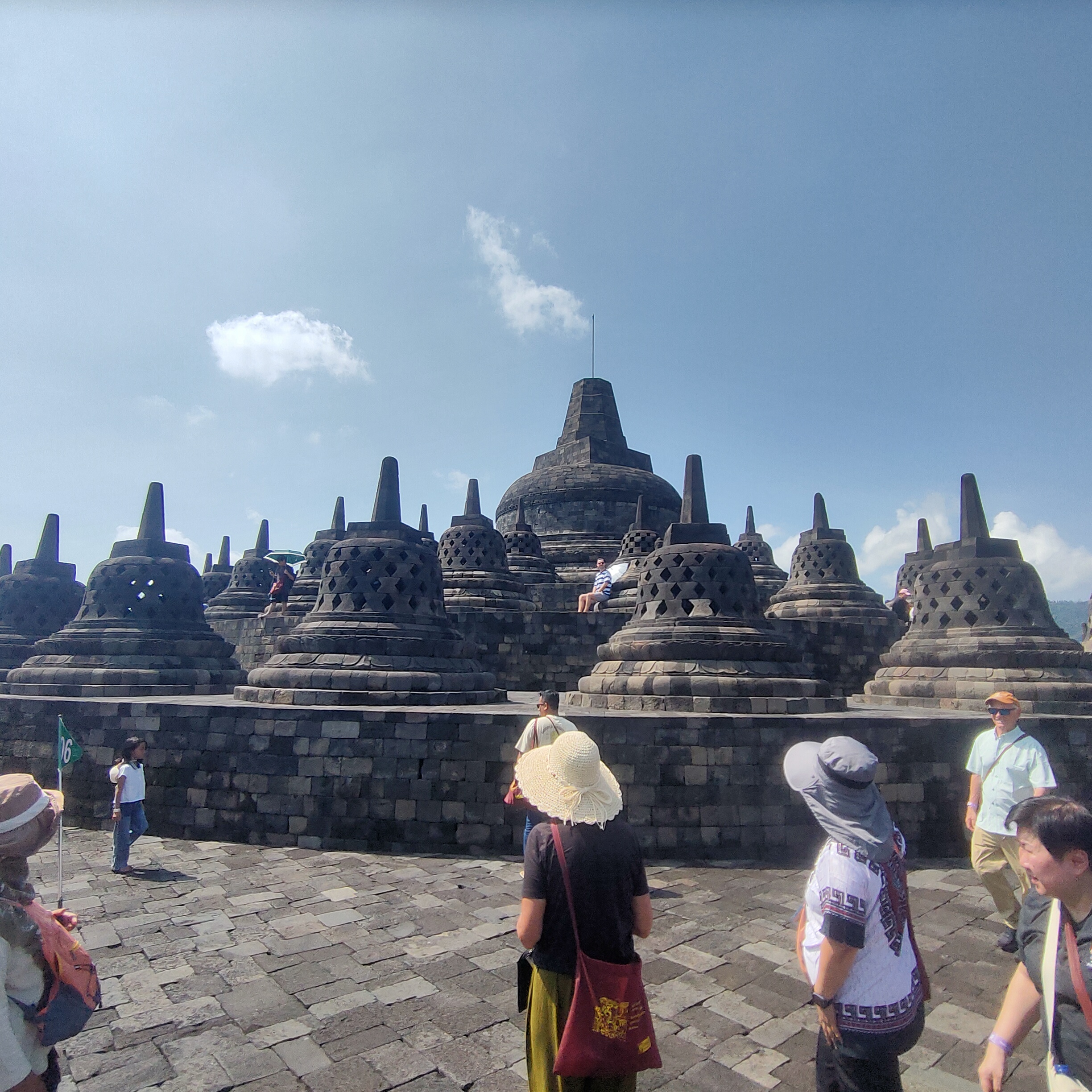 Borobudur temple upper terrace with central dome and multiple bell shaped stupas surrounded by tourists Central Java Indonesia