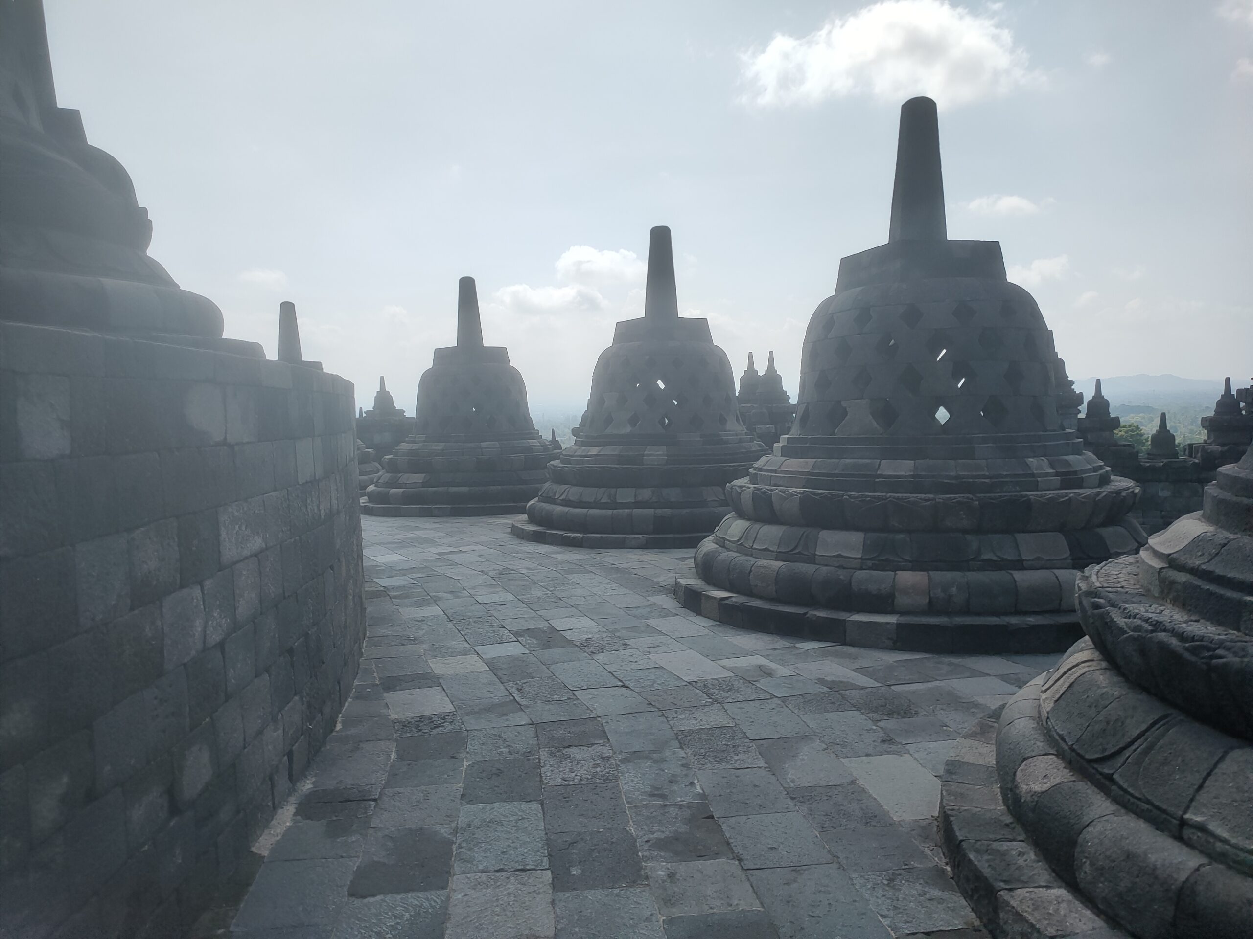 Three Borobudur stupas in silhouette with mist on upper terrace Central Java Indonesia