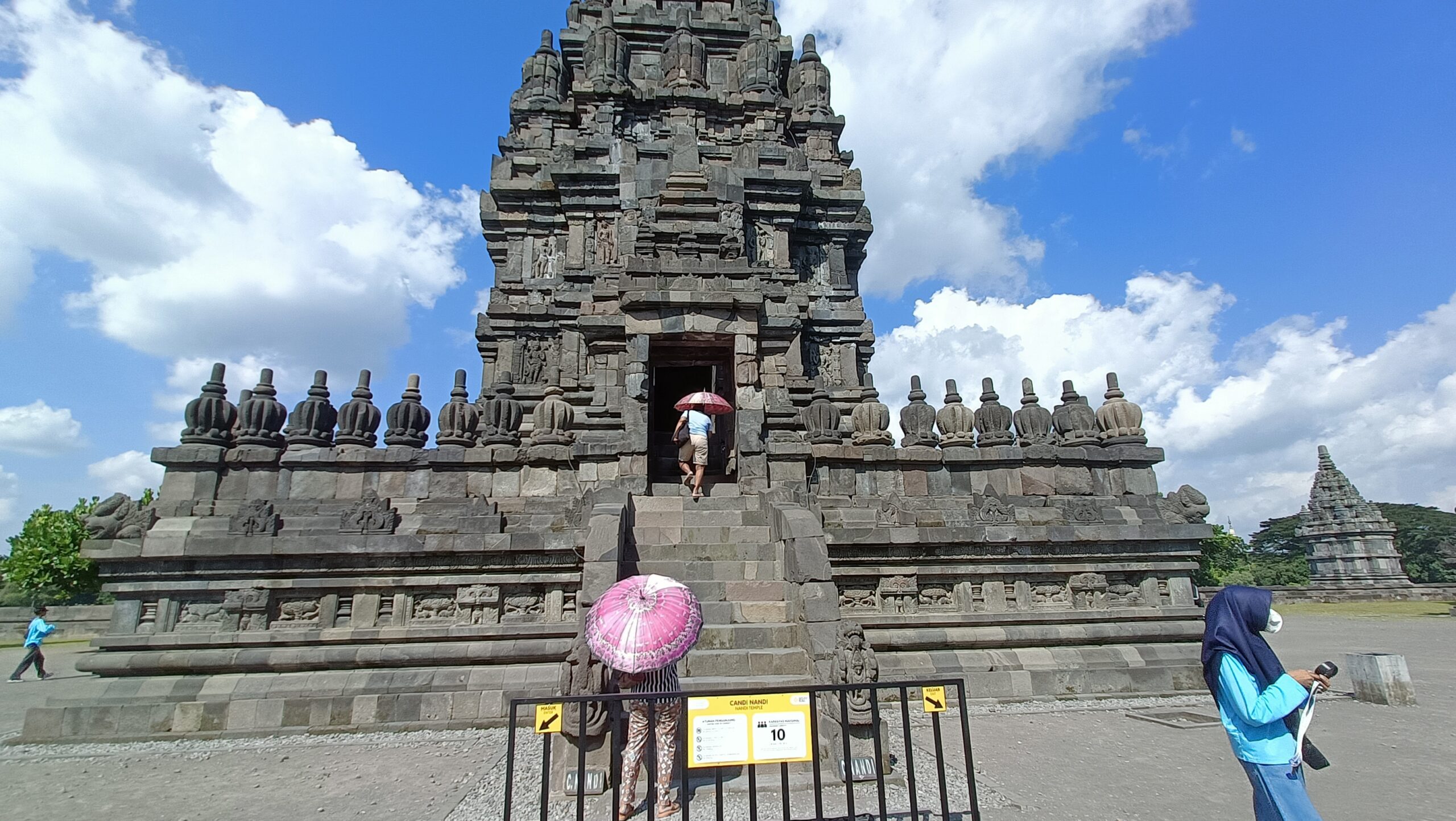 Prambanan Temple: The 00:00 Guide to Java’s Hindu Twin Candi Shiva Mahadeva main temple at Prambanan with tall stone staircase and tourist holding pink umbrella Yogyakarta Indonesia