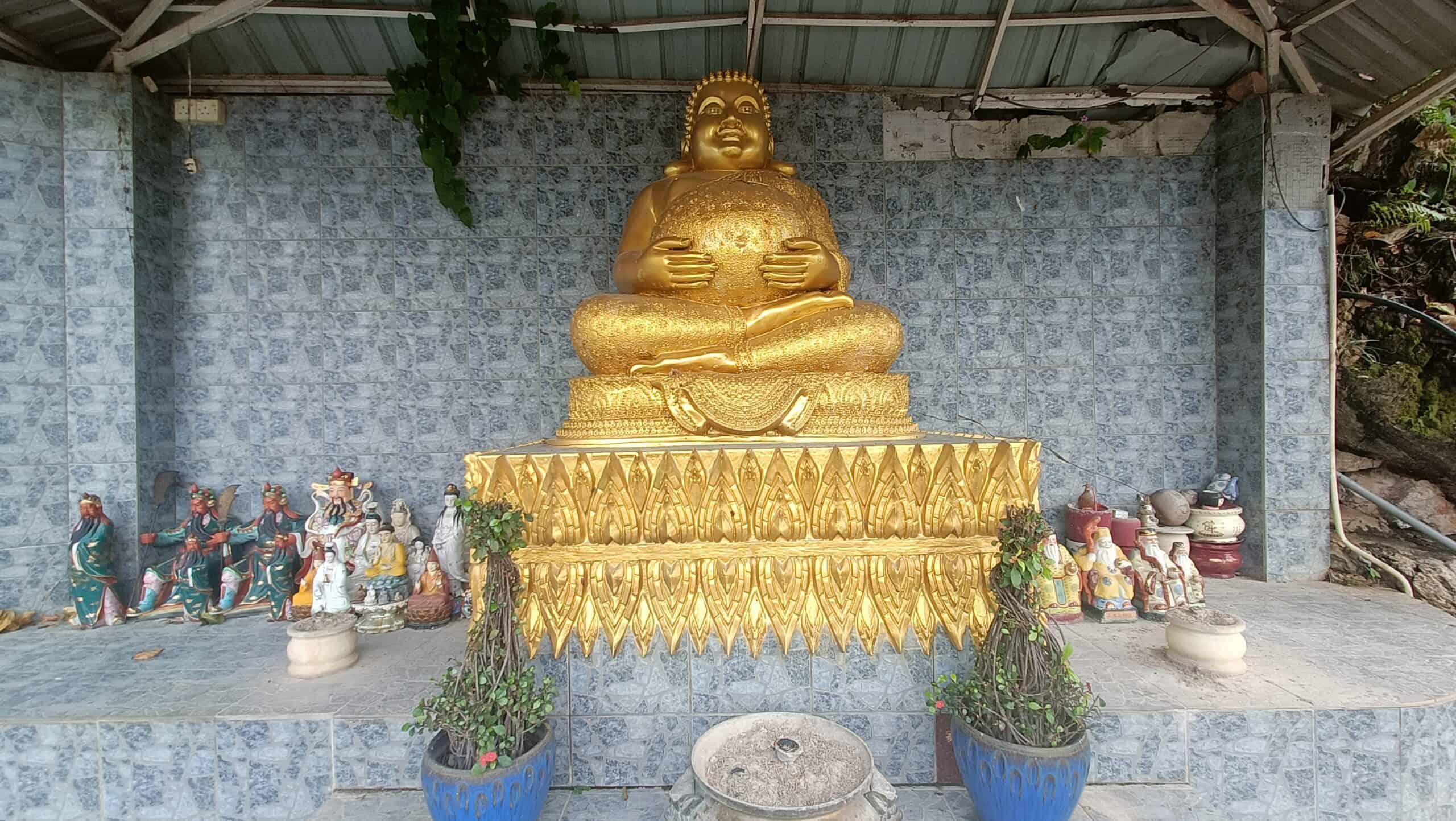 `Golden Laughing Buddha statue at Wat Puthanimittam Temple Ipoh seated on ornate golden pedestal`