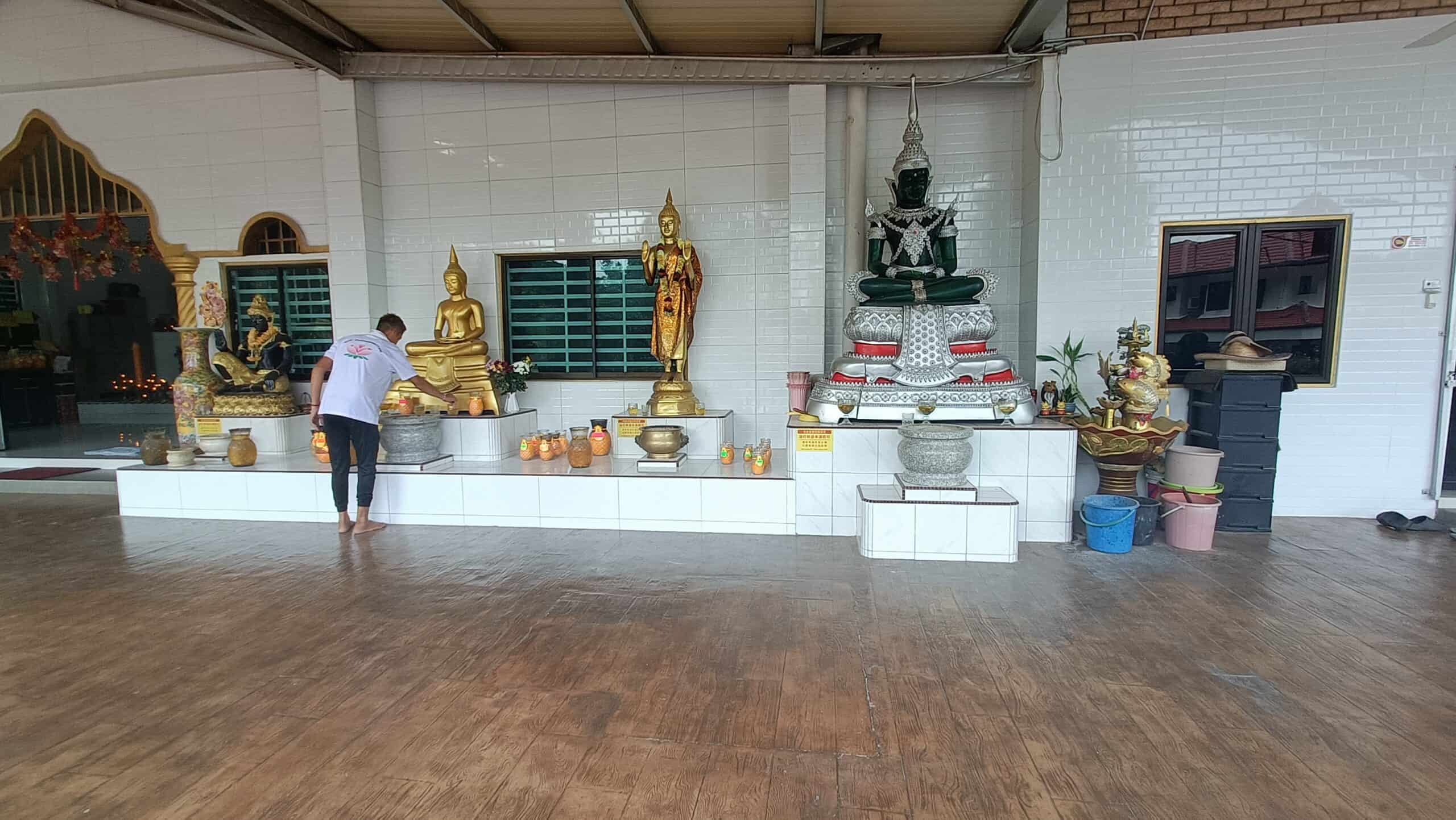 Prayer hall
`Inside the main prayer hall of Wat Puthanimittam Temple Ipoh with golden Buddha statues and a person praying at the altar`