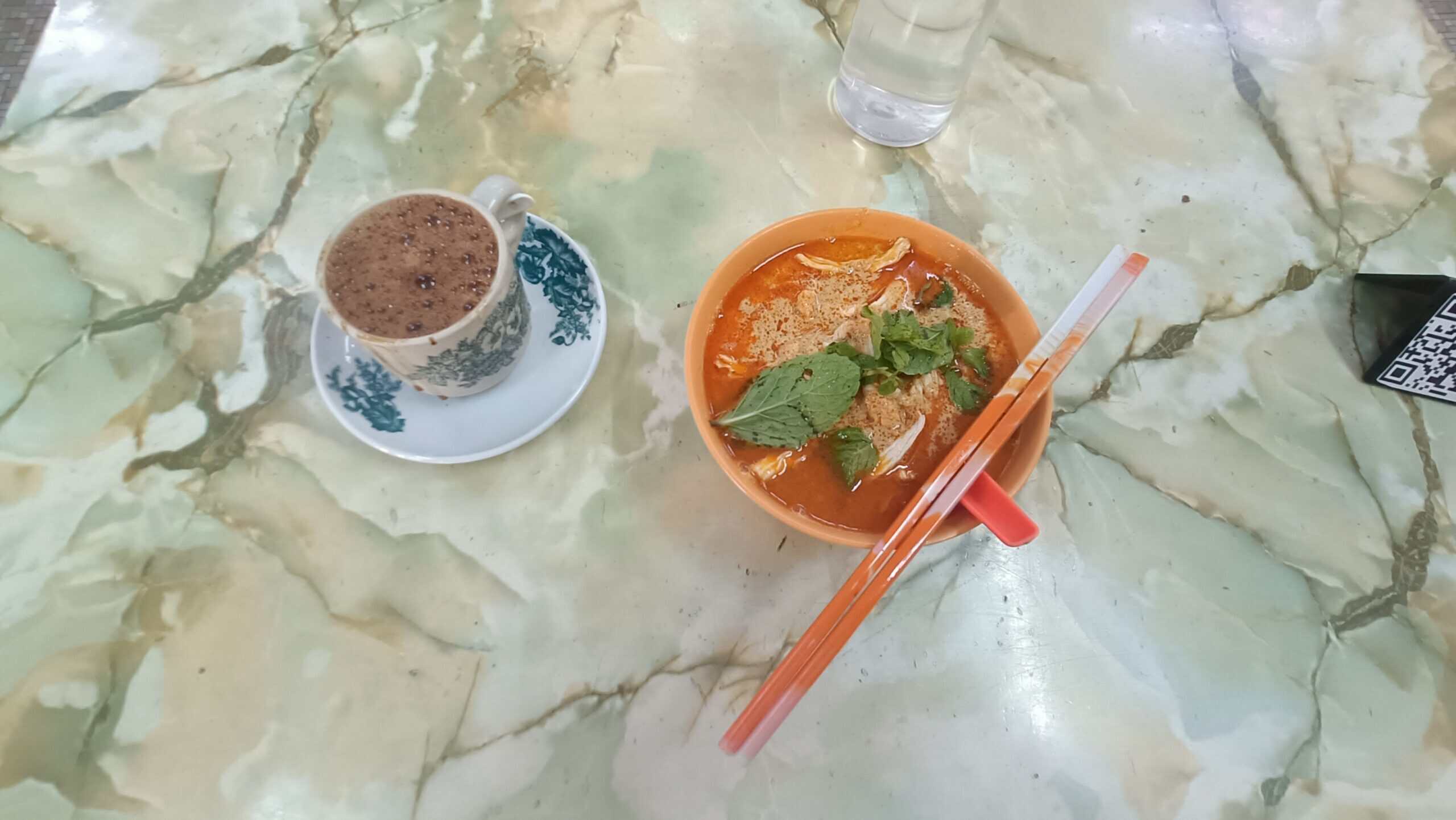 Ah Chow`Top down view of Ipoh hor fun noodles with chopsticks and coffee on marble table at Ah Chow Restaurant`