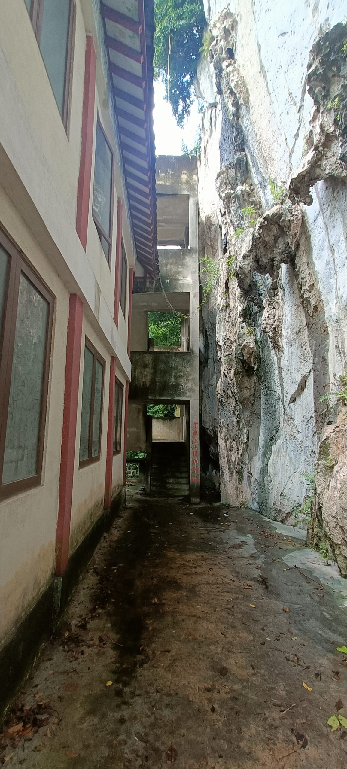 Narrow pathway between temple building and limestone rock wall at Perak Tong Cave Temple