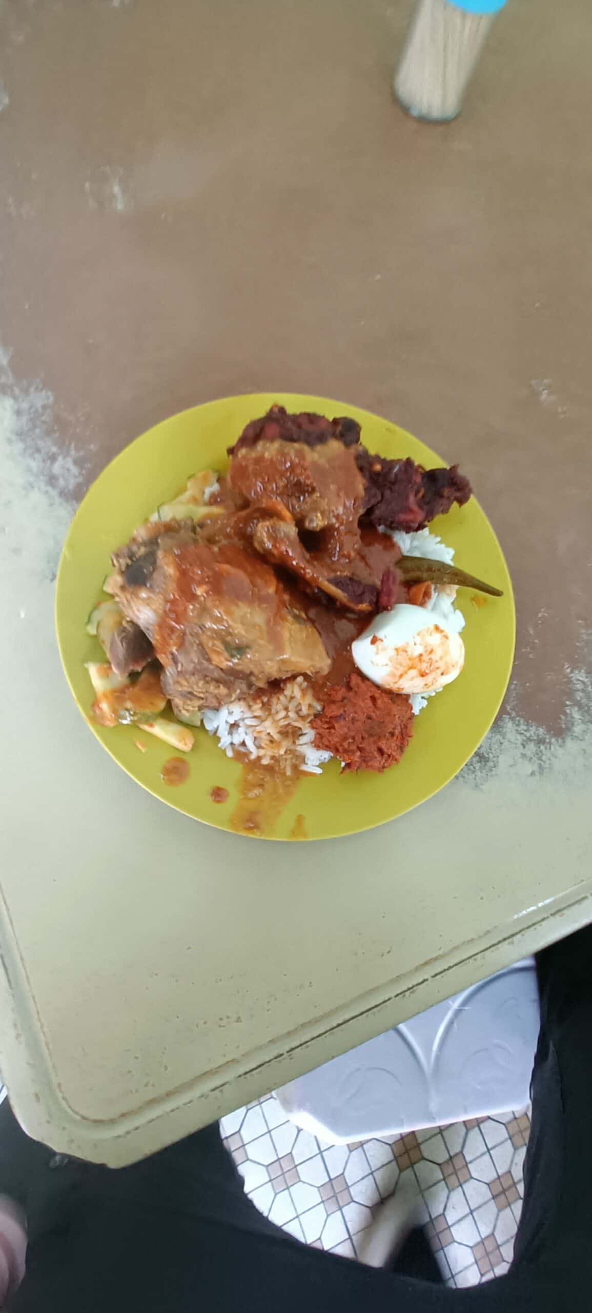 Yellow plate of Nasi Ganja with mutton, fried chicken, rice, bendi, cucumber and egg
